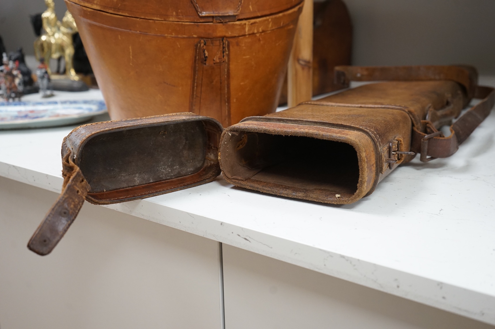 A 'Leg of Mutton' leather gun case and a top hat in leather case, gun case 75cm long.